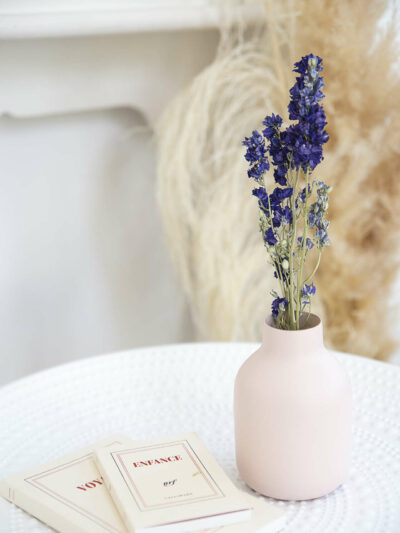 vase de couleur rose pastel avec des fleurs séchées bleues à l'intérieur