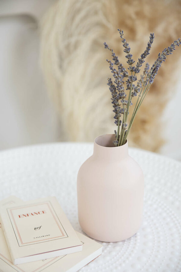 vase de couleur rose pastel avec des fleurs séchées bleues à l'intérieur