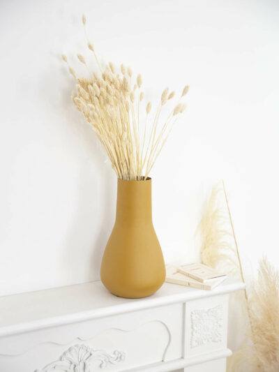 vase couleur moutarde avec des fleurs séchées blanches dedans